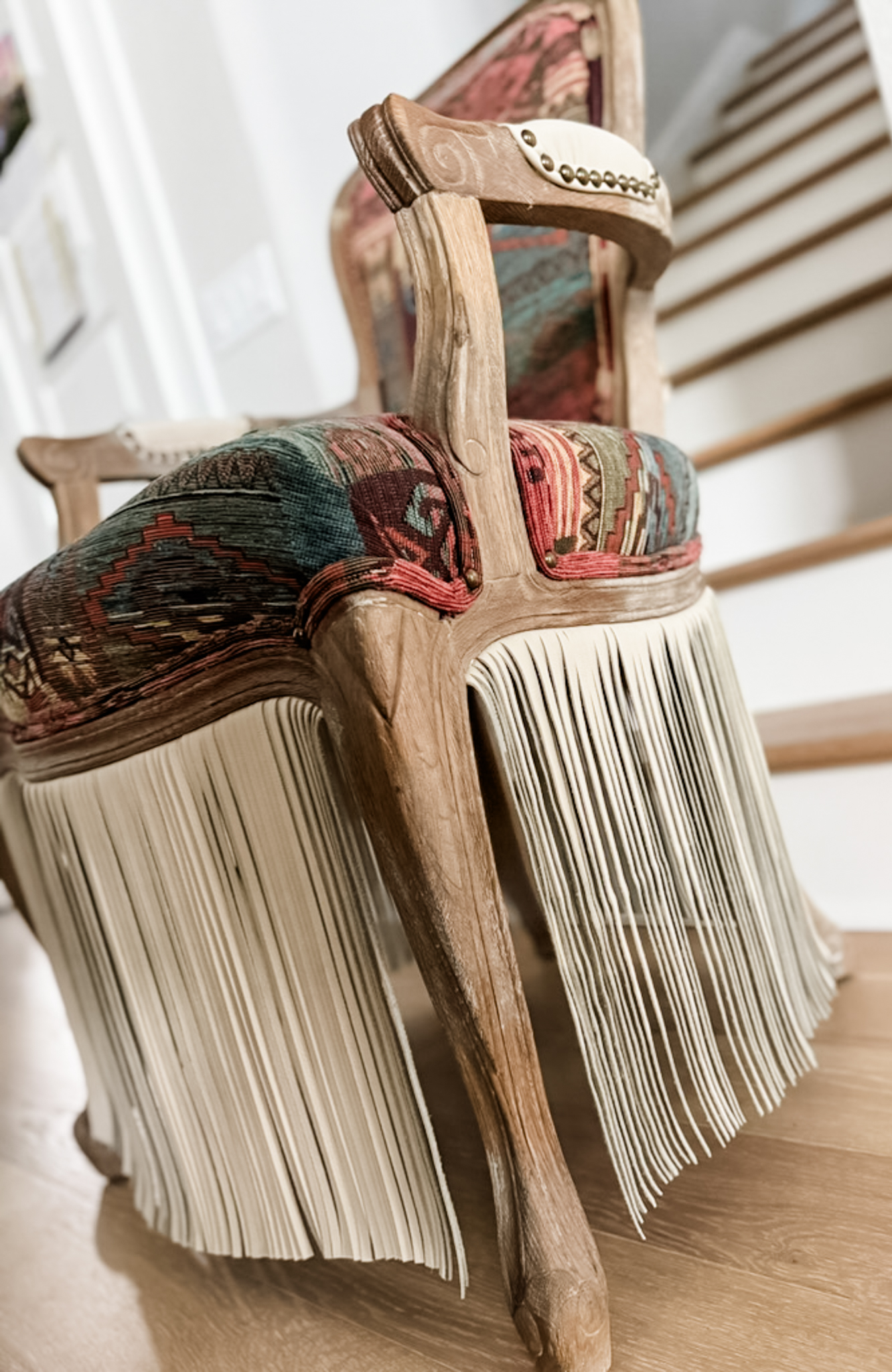 Detailed view of fringe skirt and carved legs on upholstered chair