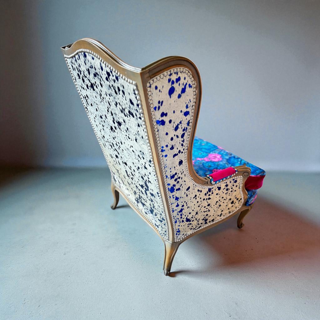 side view of electric blue acid wash cowhide wingback chair; features velvet floral pattern and a reversible cushion in fushia.