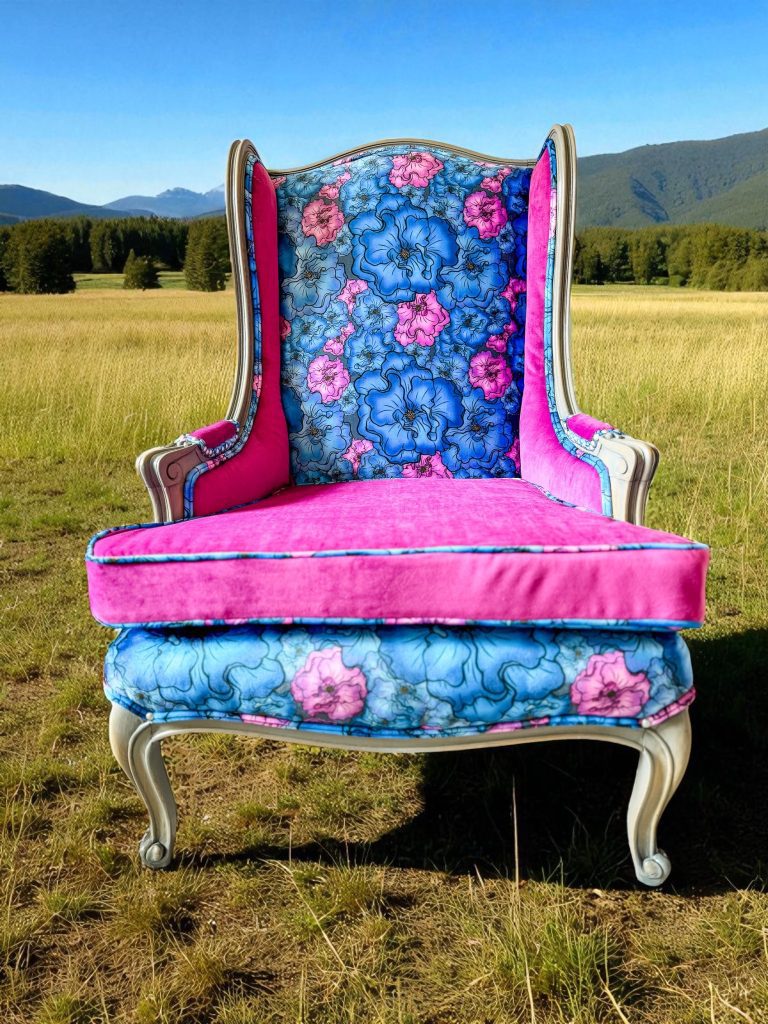 front view of electric blue acid wash cowhide wingback chair; features velvet floral pattern and a reversible cushion in fushia.