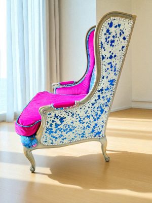 wingback cowhide chair side view of electric blue acid wash cowhide wingback chair; features velvet floral pattern and a reversible cushion in fushia.